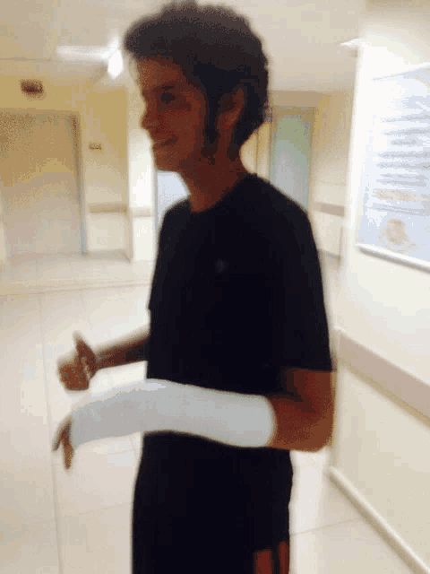 a man with a cast on his arm in a hospital hallway