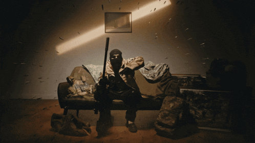 a man in a mask sits on a couch with a gun