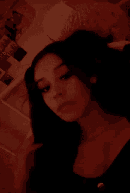 a girl is taking a selfie in a dark room with a red light on her face .