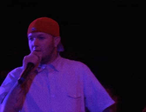 a man wearing a red hat and a white shirt is holding a microphone
