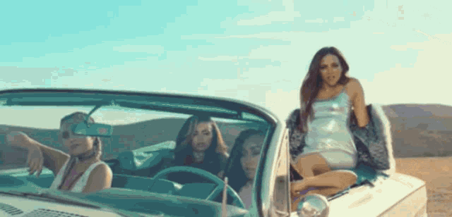 a group of women are sitting in a white convertible car