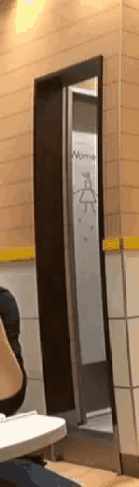a person is sitting at a table in a restaurant next to a door that is open .