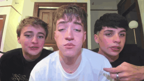 three young men are standing next to each other with one wearing a ring on his finger