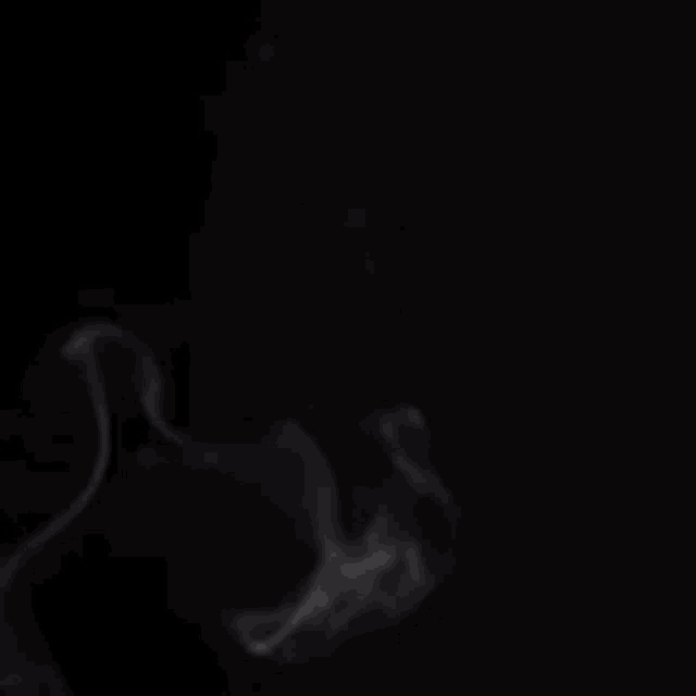 smoke is coming out of a pipe on a black background in slow motion .