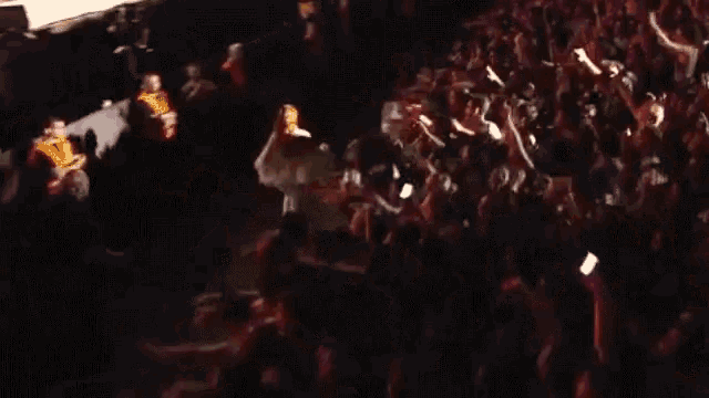 a woman in a white dress stands in front of a crowd