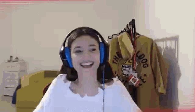 a woman wearing headphones is smiling while sitting in front of a green couch .