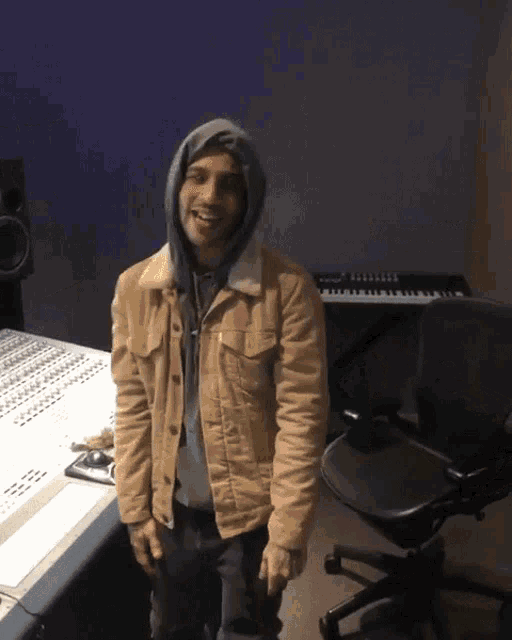 a man wearing a tan jacket and a grey hoodie