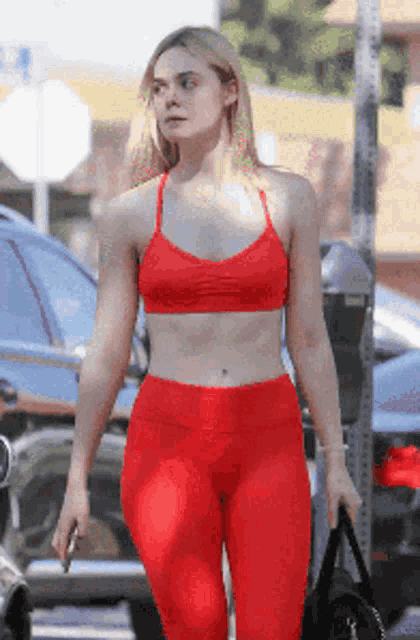 a woman wearing red leggings and a red sports bra is walking down the street