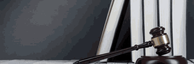 a wooden judge 's gavel is sitting on a table next to a stack of books