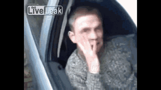a man is sitting in a car with his hand on his face and a liveleak logo in the corner