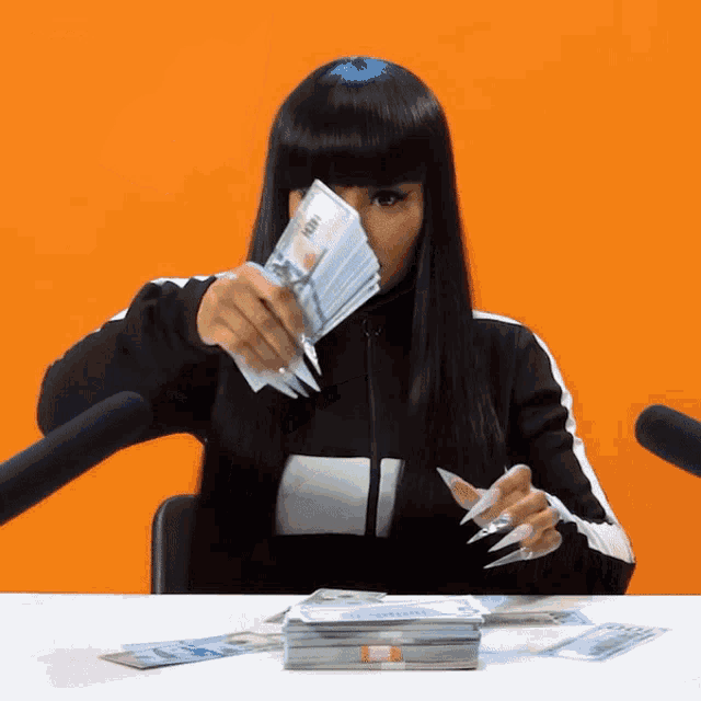 a woman is sitting at a table with a bunch of money in front of her face that says 100 on it