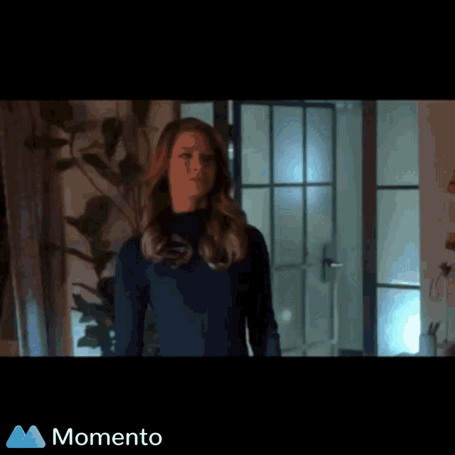 a woman in a blue suit is standing in front of a door and the word momento is on the bottom right