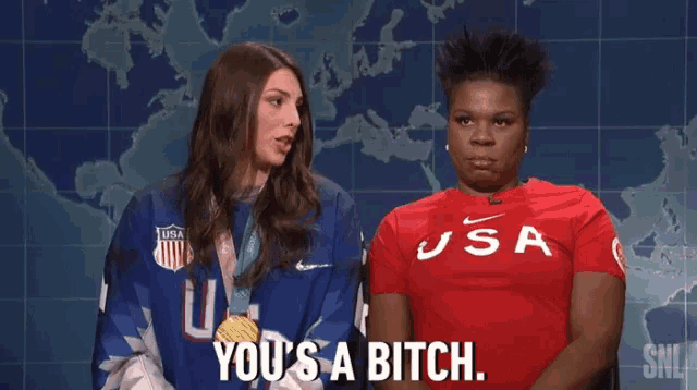 two women are standing next to each other in front of a map of the world . one of the women is wearing a usa shirt .