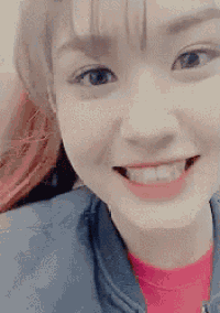a close up of a woman 's face smiling and wearing a blue jacket