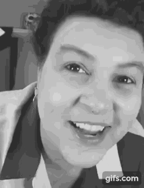 a black and white photo of a woman smiling with a nose ring .