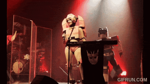 a robot playing a keyboard on stage with gifrun.com written on the bottom