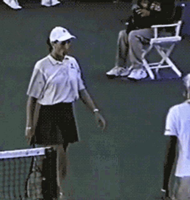 a tennis player holds a racket and talks to another player