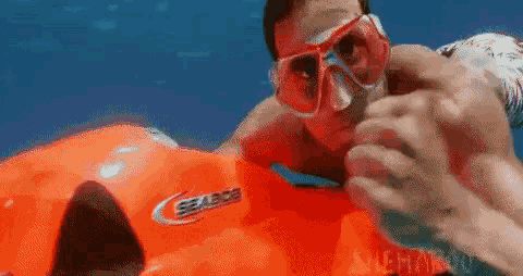 a man wearing a mask and goggles is laying on a seabob jet ski .