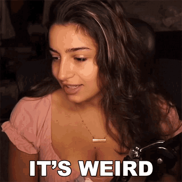 a woman in a pink top says it 's weird in front of a microphone