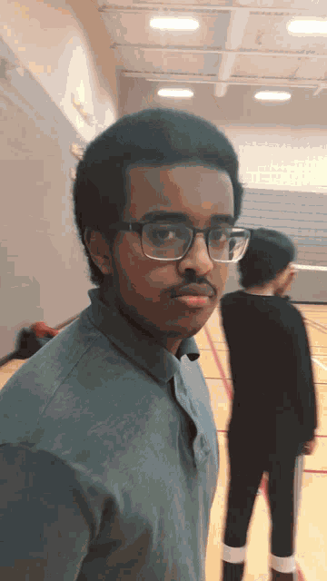 a young man wearing glasses and a green shirt looks at the camera