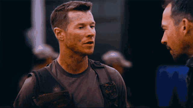 two men are talking to each other and one of them has a patch on his chest that says ' army '