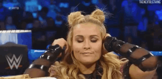 a woman is holding her hair in buns while sitting in a ring .