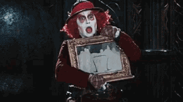the mad hatter from alice in wonderland is holding a framed picture .