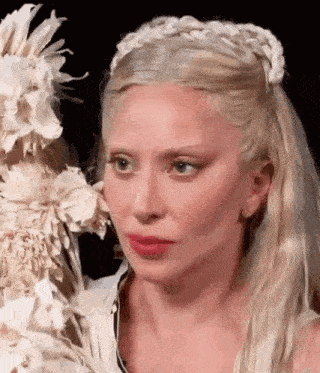 a woman with blonde hair and a braided headband is holding a cake .