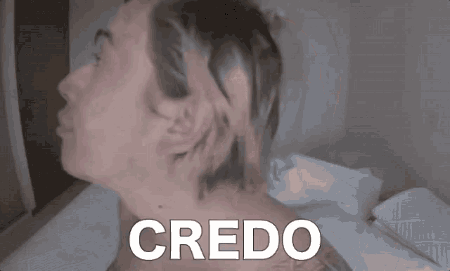 a man without a shirt is laying on a bed with the word credo above his head