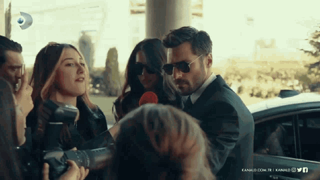 a man in a suit is talking into a microphone while a woman takes a picture
