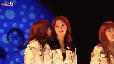 a woman with red hair is kissing another woman 's cheek