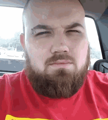 a man with a beard wears a red shirt with a yellow stripe