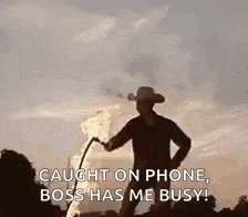 a man in a cowboy hat is holding a torch and says `` caught on phone , boss has me busy ''