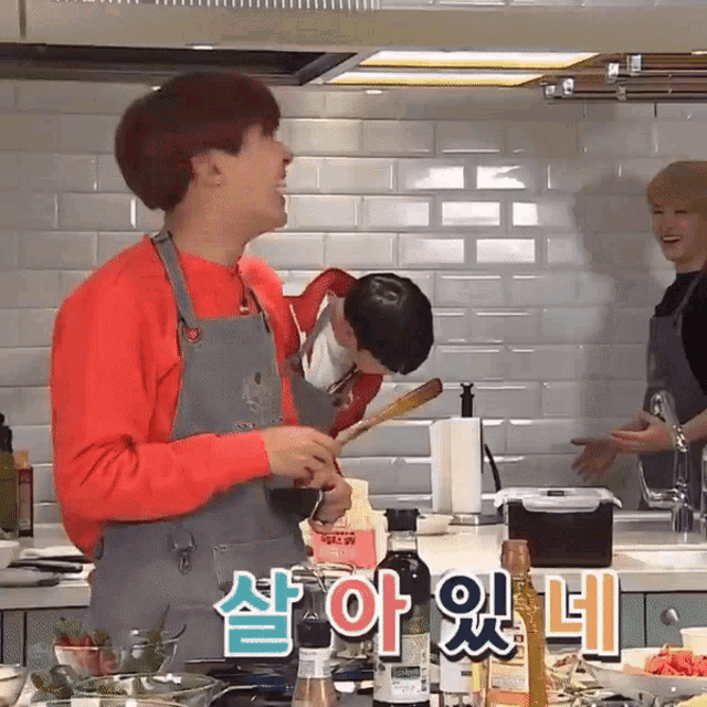 a man in a red sweater is cooking in a kitchen with korean writing on the counter