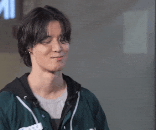 a man wearing a green hoodie with a name tag that says ' squid game ' on it