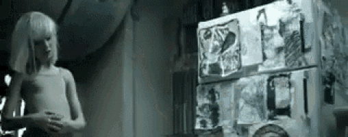 a little girl is standing in front of a refrigerator with drawings on it .