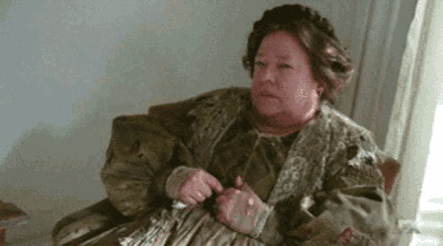 an older woman is sitting in a chair with her hands on her chest