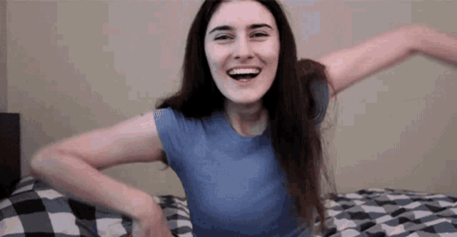 a woman is laying on a bed with her arms outstretched and smiling .