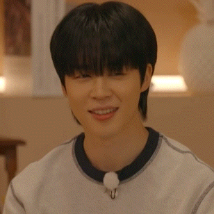 a young man wearing a white sweater and a black collar is smiling