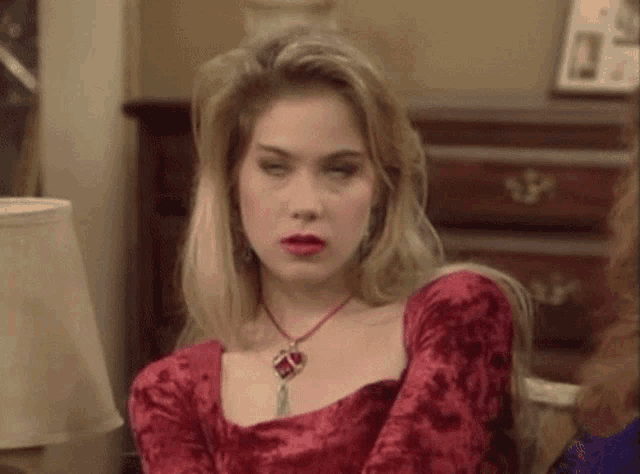 a woman in a red dress and necklace is sitting in a living room
