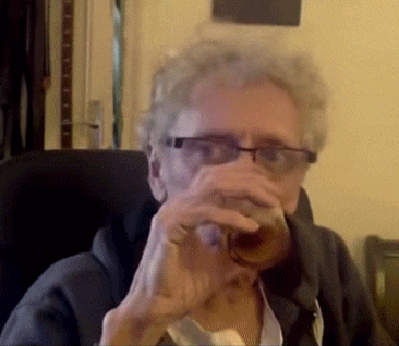 a man wearing glasses is drinking a glass of beer