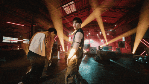 two men are dancing in a room with red lights and a sign that says ' x-box ' on it