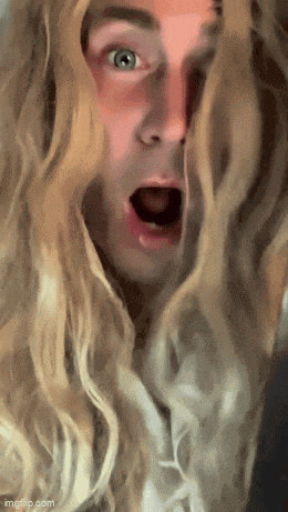 a man with long blonde hair and blue eyes is making a surprised face