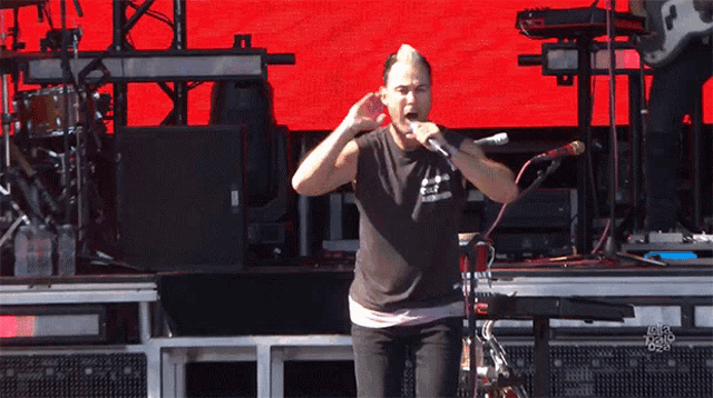 a man singing into a microphone while wearing a black shirt that says " i love you "