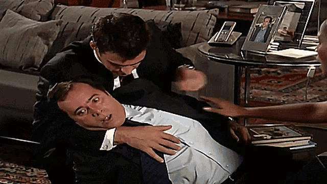 a man in a suit is laying on the floor with another man