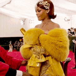a woman wearing a yellow fur coat is being helped by a man
