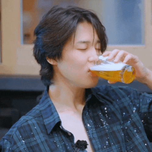 a man in a plaid shirt drinks from a glass