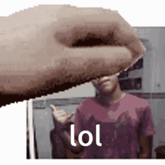 a close up of a person 's hand holding something in front of a man 's face with the word lol on it .