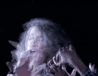 a blurry picture of a woman singing into a microphone with her hands in the air