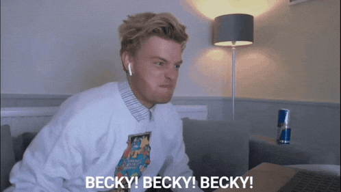 a man wearing a sweatshirt that says ' becky ' on it is sitting in front of a laptop